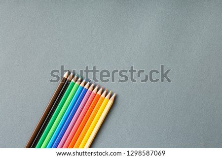 colored pencils in row on a gray background top view. Art set of pencils for schoolboy with free space. view from above
