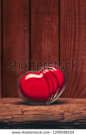 Glass red heart on a old wooden table. Beautiful dark background.