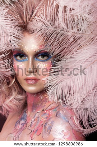 close up  portrait of young beautiful girl with colorful face painting. Halloween professional makeup. hair in paint. beauty portrait. pink and purple hair. feathers on face