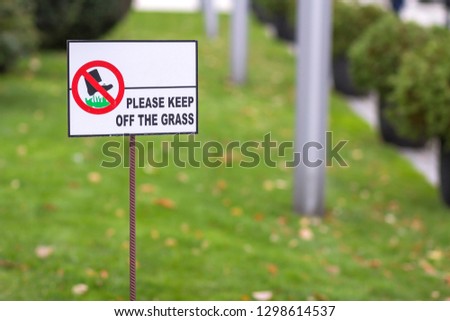 Please keep off the grass sign on green lawn grass blurred bokeh background on sunny summer day. City lifestyle and nature protection concept.