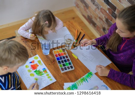 Happy children - boy and two girls is drawing with colorful paint