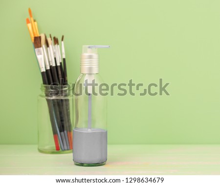 Grey paint in a pump bottle with a light green background