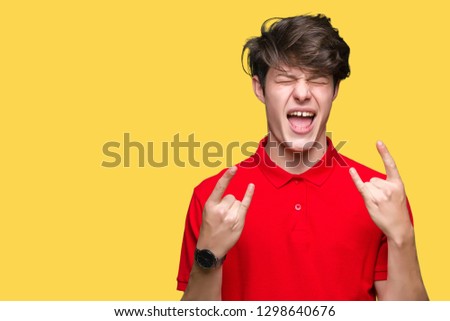 Young handsome man wearing red t-shirt over isolated background shouting with crazy expression doing rock symbol with hands up. Music star. Heavy concept.