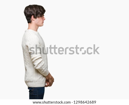 Young handsome man wearing glasses over isolated background looking to side, relax profile pose with natural face with confident smile.