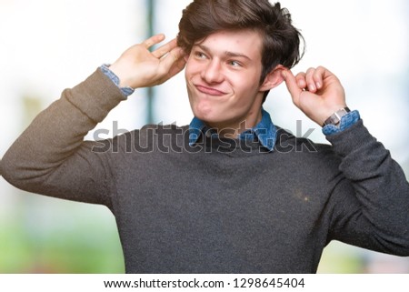 Young handsome elegant man over isolated background Smiling pulling ears with fingers, funny gesture. Audition problem