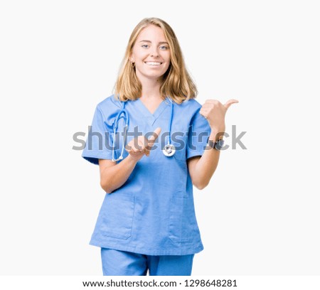 Beautiful young doctor woman wearing medical uniform over isolated background Pointing to the back behind with hand and thumbs up, smiling confident