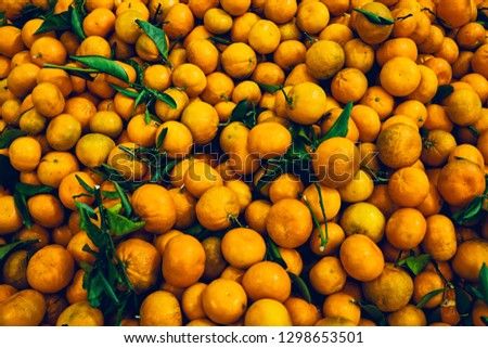 Large pile of raw oranges with stems and leaves at a farmers market in southern california. 