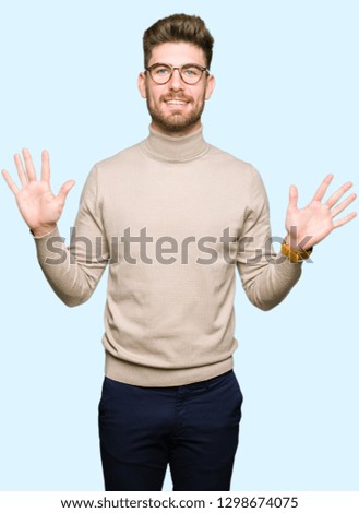 Young handsome business man wearing glasses showing and pointing up with fingers number ten while smiling confident and happy.