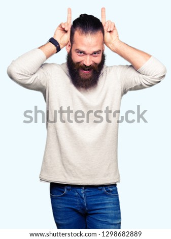 Young blond man wearing casual sweater Posing funny and crazy with fingers on head as bunny ears, smiling cheerful