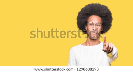 Young african american man with afro hair wearing glasses Pointing with finger up and angry expression