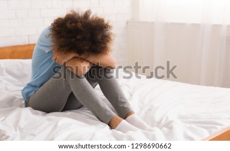 African-american woman suffering from depression sitting on bed, empty space