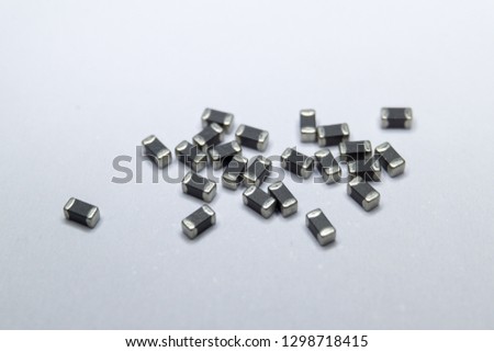 Abstract close-up of grey scattered 0402 SMT surface mount chip ferrite bead power electronics components on white background in random pattern Royalty-Free Stock Photo #1298718415
