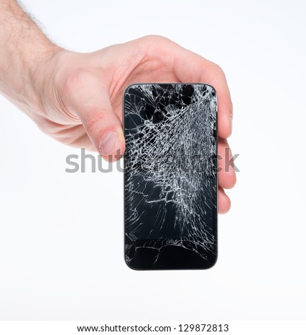 Studio closeup of a male hand, holding a smartphone with cracked screen, isolated on  white background.