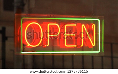 A green and orange neon "open" sign in a shop window