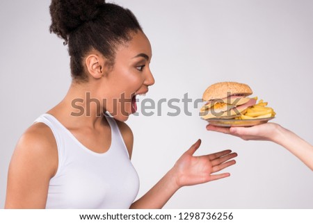 Black girl is glad about cheeseburger isolated on white background.