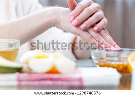 The woman applying the cream on her hands moisturizing and nourishing them with natural cosmetics close-up. Concept of hygiene and care for the skin