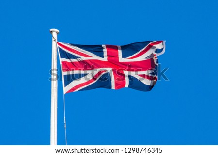 A view of a Union flag flying over a clear blue sky.