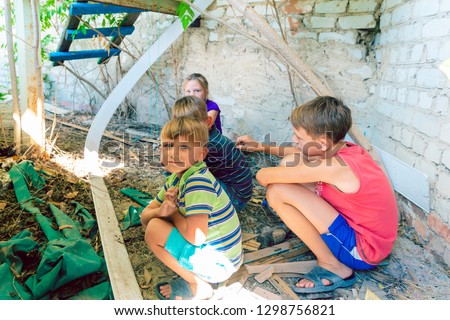 Street children sit in the trash in the corner of an abandoned house. Staged photo.