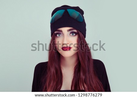 Serious young beautiful brunette teenager, hipster young woman in trendy cap with sunglasses looking at you isolated green background. Closeup confident student. Positive human emotion face expression