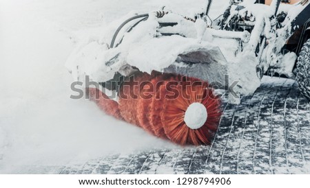 Tractor cleans road from snow after blizzard or heavy snowstrom. Cleaning or plowing snow. Bad winter weather conditions and transport service concept.
