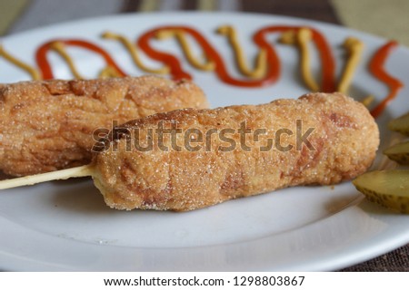home made corn dogs on a white plate. corn dogs with ketchup and mustard