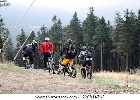 Group or team of four cyclists in a forest. Back view of four unrecognizable young men on moutain bikes wearing protective helmets and backpacks. Active lifestyle. Holiday cycling trip.