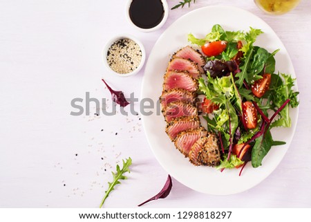 Japanese traditional salad with pieces of medium-rare grilled Ahi tuna and sesame with fresh vegetable salad on a plate. Authentic Japanese food. Top view. Copy space. Royalty-Free Stock Photo #1298818297