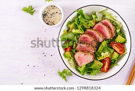 Tuna salad. Japanese traditional salad with pieces of medium-rare grilled Ahi tuna and sesame with fresh vegetable on a bowl. Authentic Japanese food. Top view Royalty-Free Stock Photo #1298818324