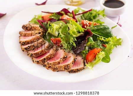 Japanese traditional salad with pieces of medium-rare grilled Ahi tuna and sesame with fresh vegetable salad on a plate. Authentic Japanese food. Royalty-Free Stock Photo #1298818378
