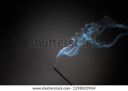 Smoking incense stick with smoke going up on Black Background. Pure relaxation theme, smoke steam, smoke waves, fog and mist effect