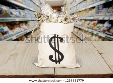 Sack with dollar sign filled with money on light blurred background