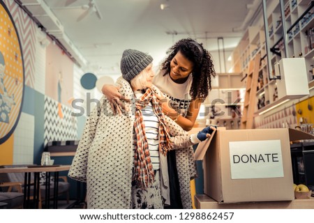 You need it. Nice joyful woman smiling while giving her old coat to a pleasant aged woman Royalty-Free Stock Photo #1298862457