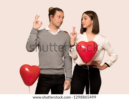 Couple in valentine day with fingers crossing and wishing the best over isolated background