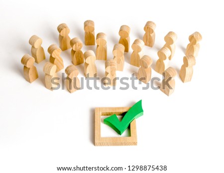 A crowd of people looks at a green check mark. Voting and election concept. Referendum, revolution. Forcible overthrow. Making the right decision, majority agreement. Peace and order, legitimization. Royalty-Free Stock Photo #1298875438