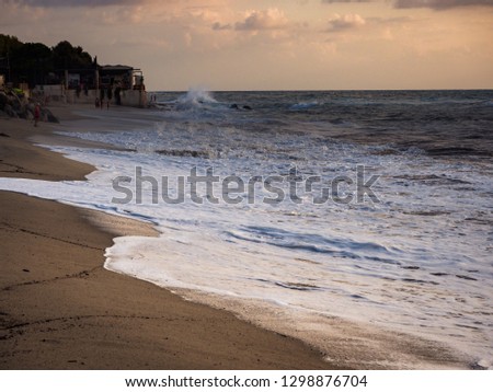 Sunset beach with rough sea and crashing waves.