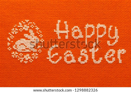 On the canvas embroidered inscription of happy Easter and rabbit.