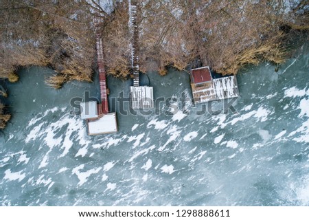 Aerial view of winter frozen lake with wooden houses on pier