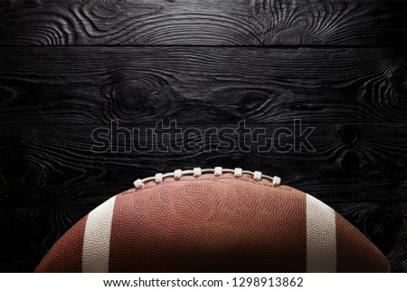 American football ball on black background illuminated by the light