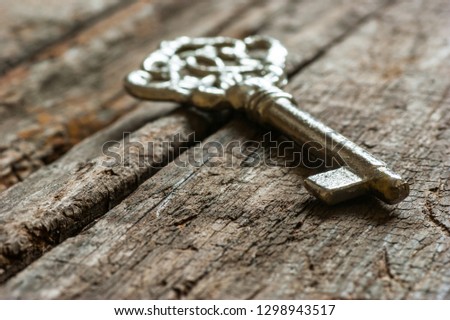 ancient, old metal key on chestnut rustic wooden background. Antique concept