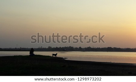 Man with dog beside the river in the evening