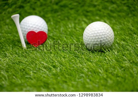 Golf ball with love shape and white tee on green grass for golf lover