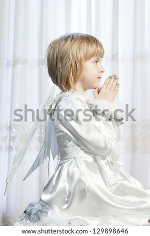 small blonde girl wearing little angel costume praying