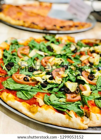 Fresh Pizza on Table with Arugula Artichoke Olives Cheese and Tomato Sauce