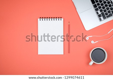 Modern red office desk table with laptop and blank notebook page for input the text. Top view, flat lay