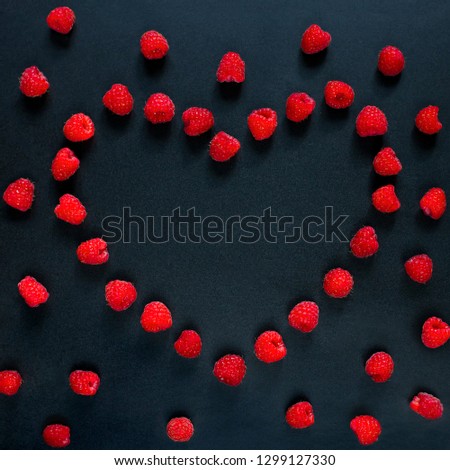Beautiful template for greeting card Happy Valentine's Day. Frame of red raspberry berries in shape of heart on black background. Top view, Flat lay. Square Valentine mockup Web banner, Copy Space