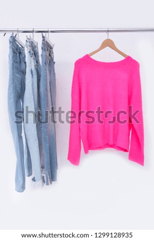Blue jeans with pink sweater on a hanger-white background
