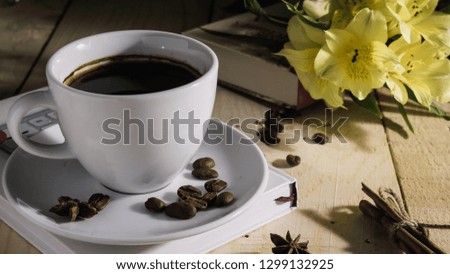 a cup of coffee and yellow flowers and a book on wooden background