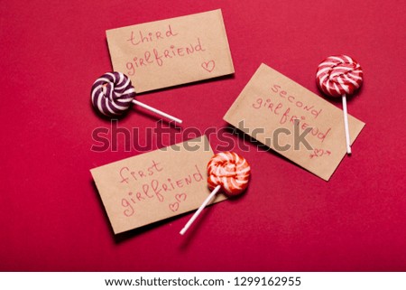 Striped lollipop red, orange, white with gift card on red background.  Valentine day, woman day, love day concept. Copy space. Free space for text. Inscription on craft card for first girlfriend. 