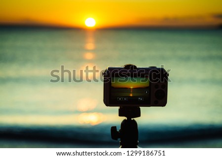 Professional camera taking picture film video of sunrise over sea surface, Greece