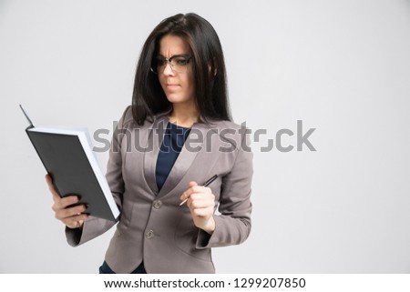 Portrait of a young girl with glasses with a diary in her hands isolated on a light background